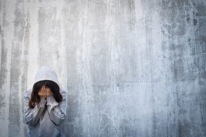 Depressed and loneliness girl crying over grunge concrete wall after using drugs or drunk alcohol. Drugs addiction and withdrawal symptoms concept. International Day against Drug Abuse. Copy space.